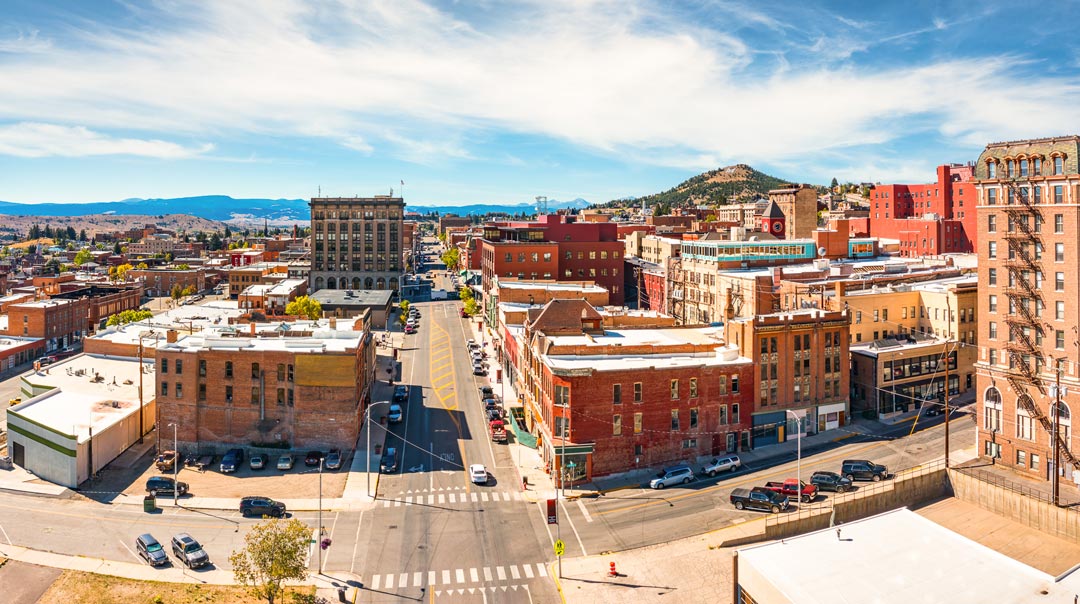 A brightly colored photo of uptown Butte Montana on a sunny day. The brick buildings in the foreground and the "M" off to the right in the background.