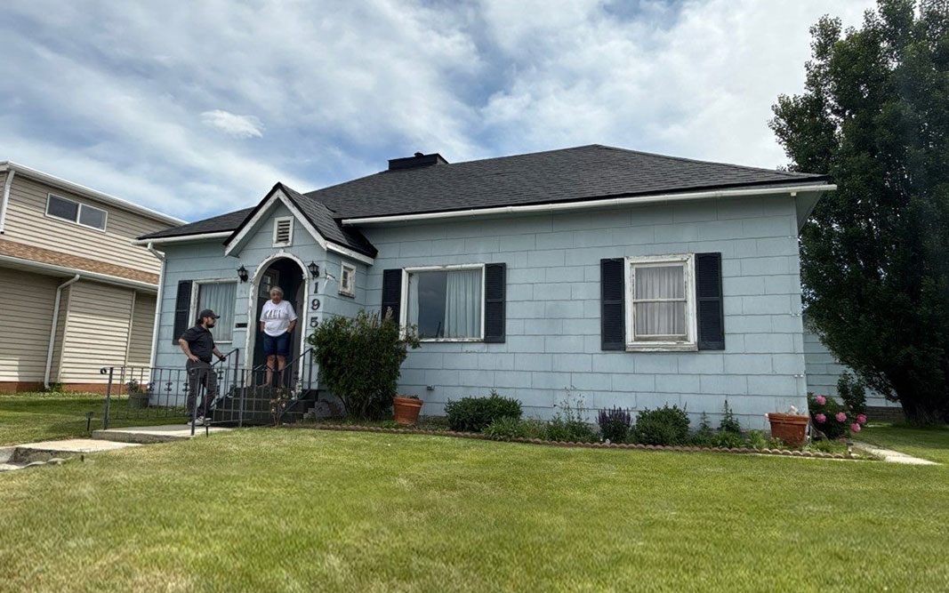 Southwest Montana Roofing Services Roofing expert John and homeowner Carol Ann visit on her steps following a final inspection of her new roof. Mountain Roofing worked with Carol Ann to get her roof claim approved by insurance after she sustained wind damage.