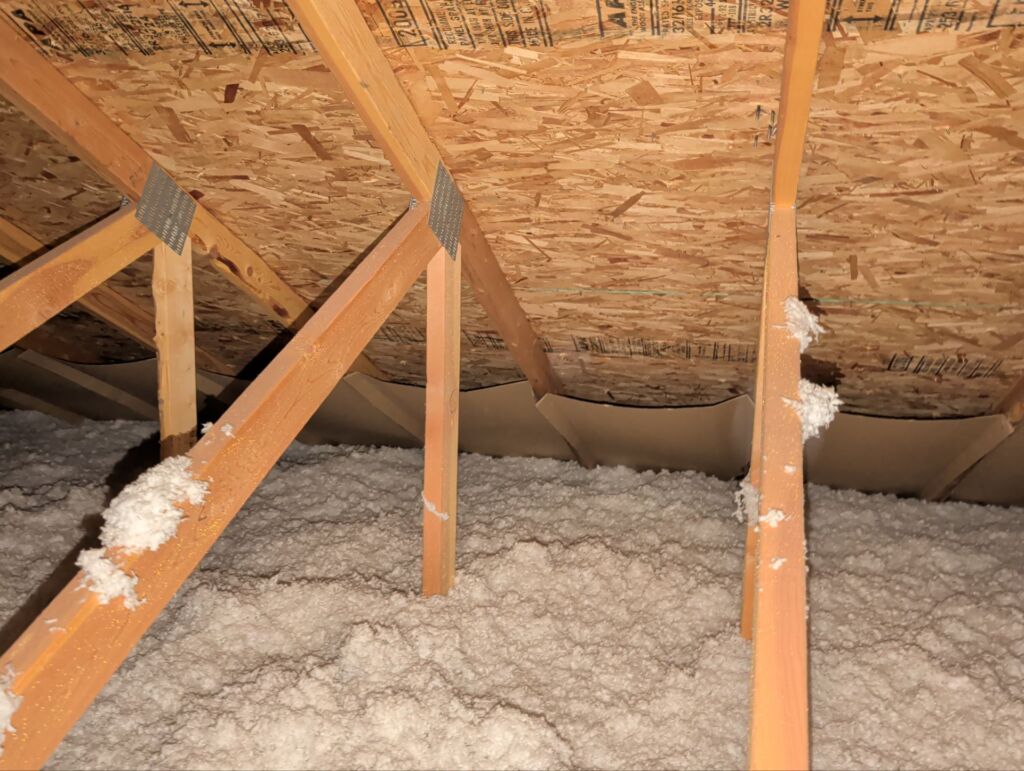 Proper residential roofing attic ventilation with baffles installed to prevent the blown-in insulation from blocking the intake vents in the soffits.