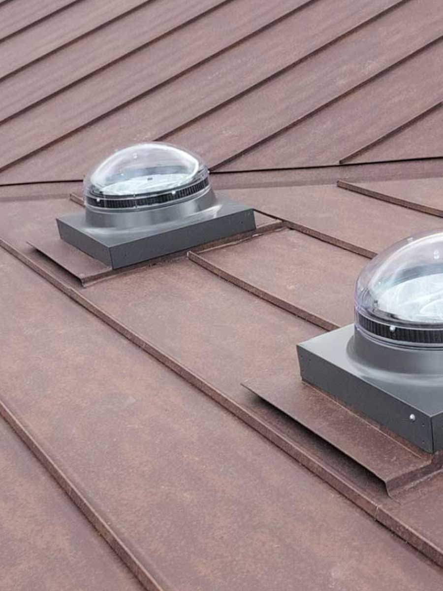 Standing Seam Metal Roof Solar Tube Flashing Details A close up detail shot showcasing custom flashings for solar tubes on a standing seam metal roof in rustic rawhide.